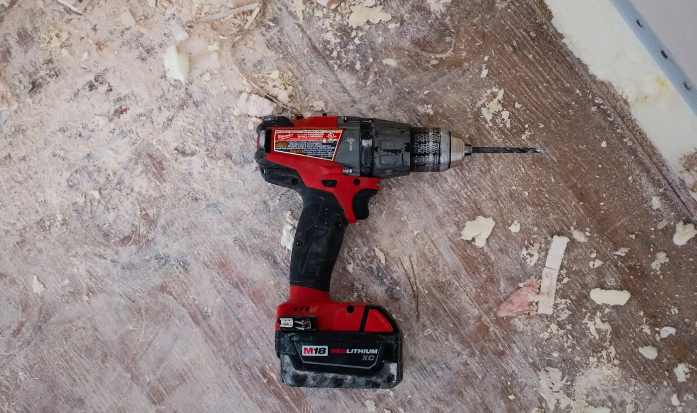 A cordless drill resting on a subfloor part-way through a job